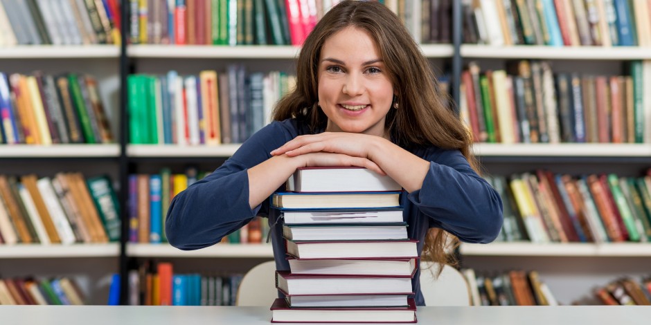 A college student displays a stack of textbooks.